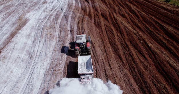 Tractor applying limestone to the soil to correct acidity