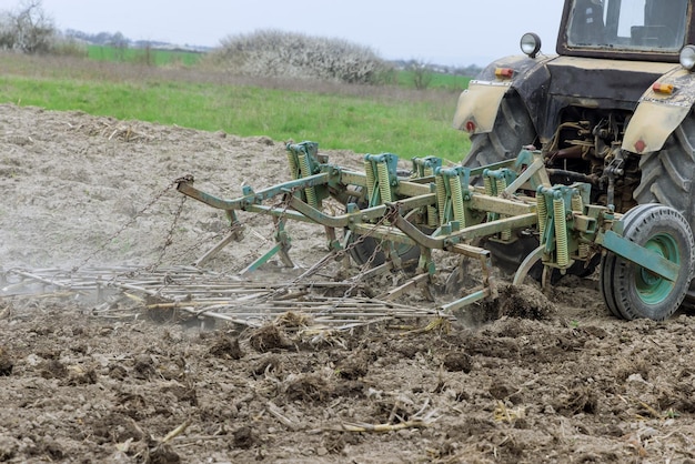 Tractor cultivates and loosening soil on farm field