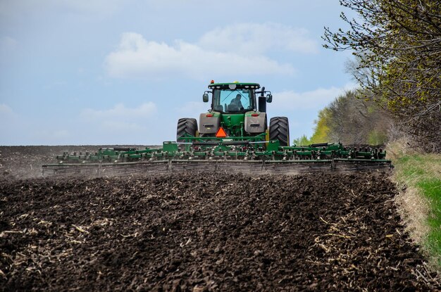 Tractor cultivating field on cloudy spring day