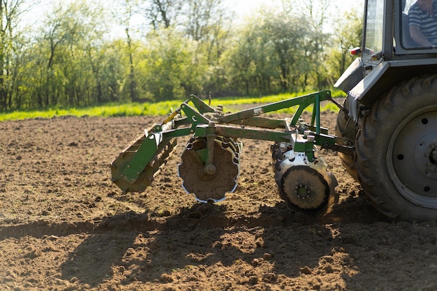 The tractor drives across the field and cultivates the land Agricultural vehicle works in countryside Sowing is the process of planting seeds in the ground as part of the early spring time