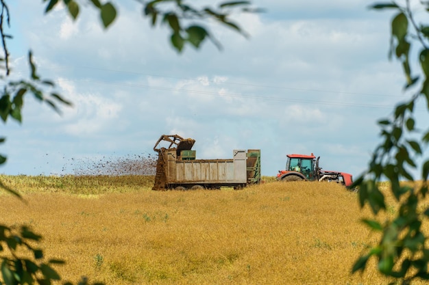 A tractor in the field scatters natural fertilizers The use of fertilizers to accelerate plant growth Agricultural field and working machinery