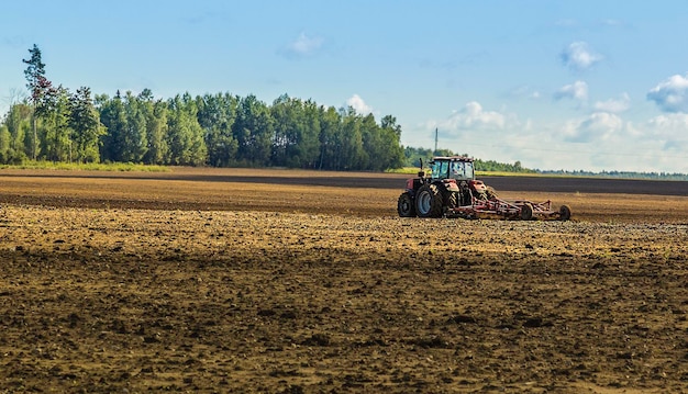 Tractor plowing cereal field with sky with clouds Copy space