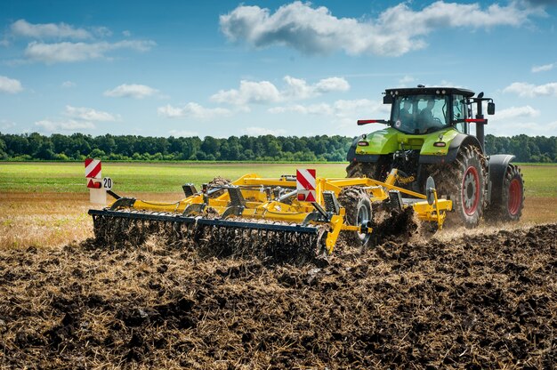 The tractor pulls a disc cultivator, the tillage system in the field is preparing for the new season