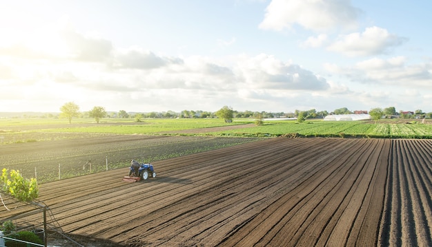 A tractor rides on a farm field Farmer on a tractor with milling machine loosens grinds and mixes soil