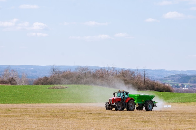 Tractor spreading fertilizer on grass field. Agricultural work.