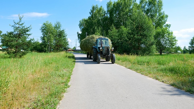 Tractor transports hay in the village.