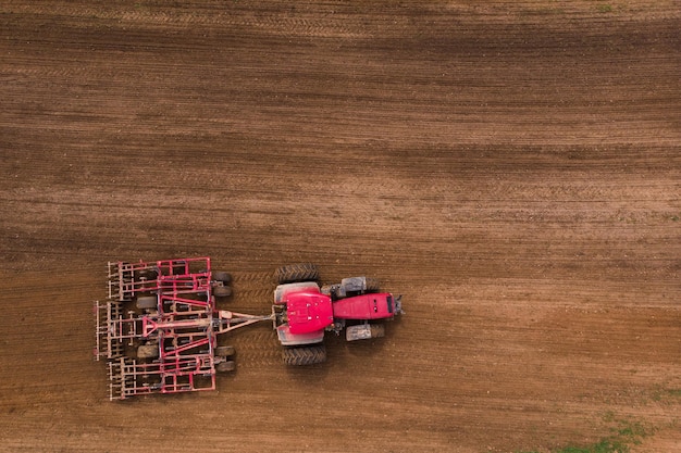 A tractor with a disc harrow plows a field for sowing Aerial photography