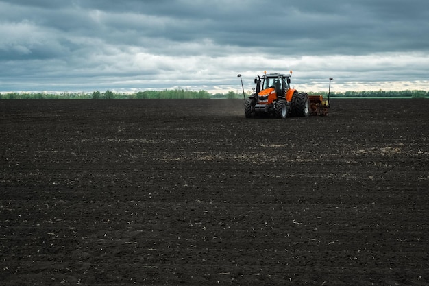 A tractor with a seed drill is engaged in planting grain crops