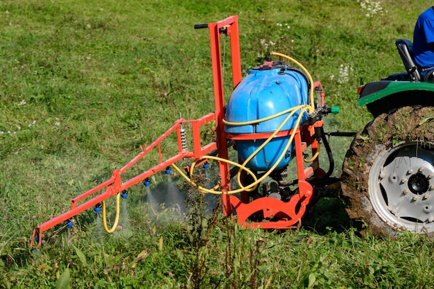 A tractor with a tank and attached equipment for spraying the field from pests and weeds