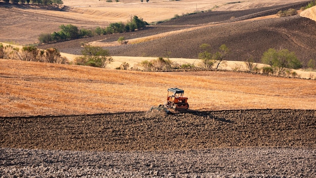 Tractor working on farming lands countryside landscape in Tuscany Italy