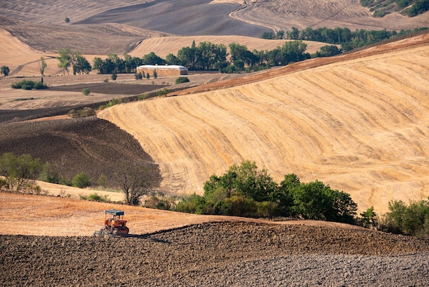 Tractor working on farming lands countryside landscape in Tuscany Italy