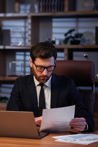 The trader checks the exchange rates Man portrait in cinematographic light Handsome businessman is working in the office