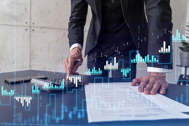 A trader computing historic data to predict stock market behavior Internet trading concept Forex and financial hologram chart over the desk and calculator