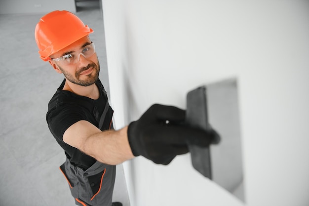 Photo tradesman on stilts plastering drywall in home