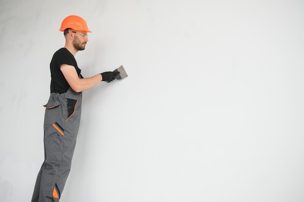 Photo tradesman on stilts plastering drywall in home