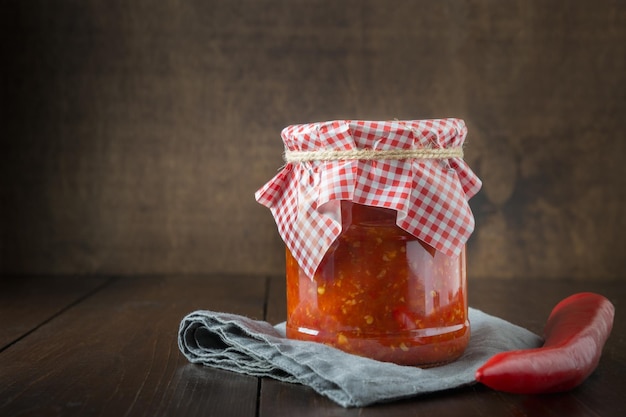 Traditional ajvar adjika from red pepper sauce paste harissa on wooden board Tunisia georgian and arabic cuisine Space for text