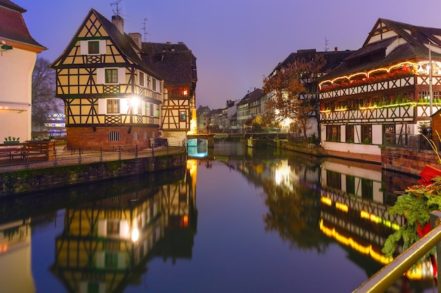 Traditional Alsatian half-timbered houses with mirror reflections in Petite France during twilight blue hour decorated and illuminated at christmas time, Strasbourg, Alsace, France