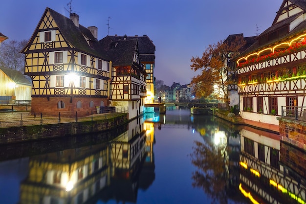 Traditional Alsatian halftimbered houses with mirror reflections in Petite France during twilight blue hour decorated and illuminated at christmas time Strasbourg Alsace France