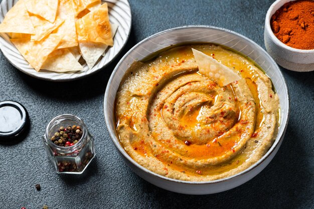 Traditional arabian eggplant dip baba ganoush with herbs and smoked paprika on dark background. Eggplant hummus. Babaganush or eggplant caviar. Baked eggplant. Turkish eggplant dip