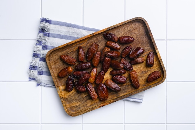 Traditional arabic dry dates set on white ceramic squared tile table background top view flat lay