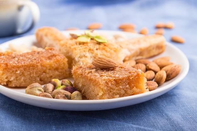 Traditional arabic sweets basbus kunafa baklava a cup of coffee and nuts on a gray concrete background side view selective focus