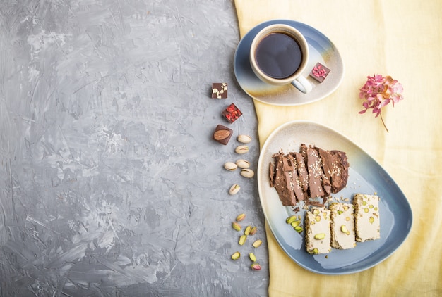 Traditional arabic sweets sesame halva with chocolate and pistachio and a cup of coffee on gray concrete 