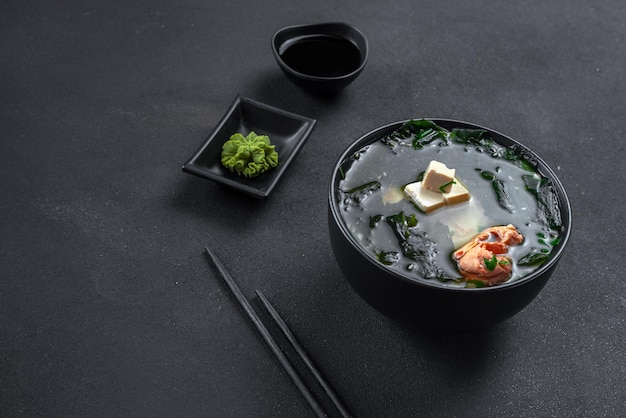 Traditional asian soup on a black background miso soup with salmon