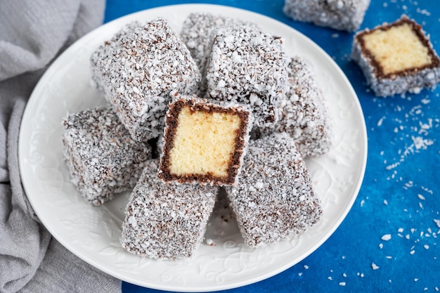 Traditional Australian Lamington cake in chocolate glaze and coconut flakes on a white plate