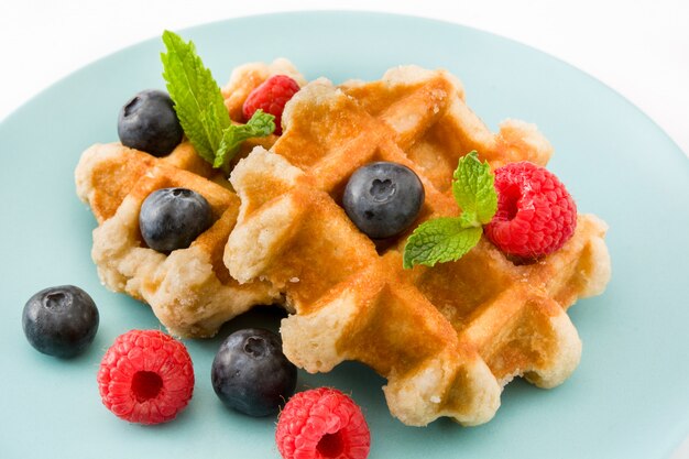 Traditional belgian waffles with blueberries and raspberries, isolated on white background