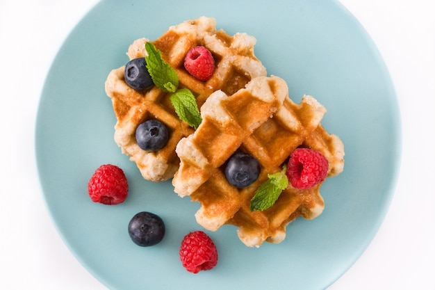 Traditional belgian waffles with blueberries and raspberries, isolated on white.