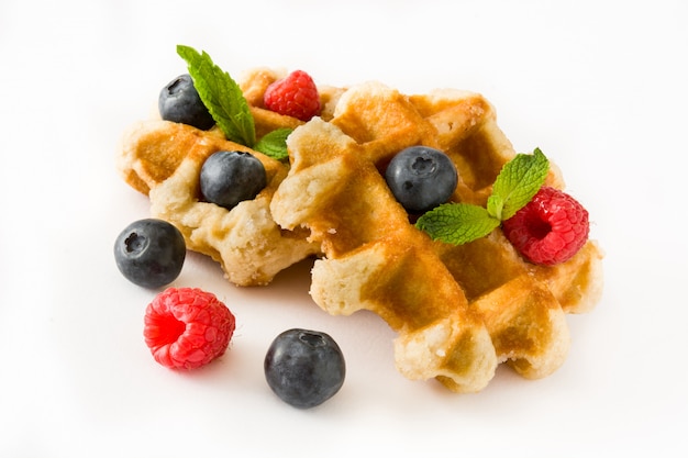 Traditional belgian waffles with blueberries and raspberries isolated on white.