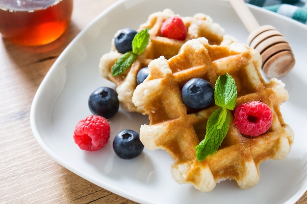 Traditional belgian waffles with blueberries and raspberries on wooden table