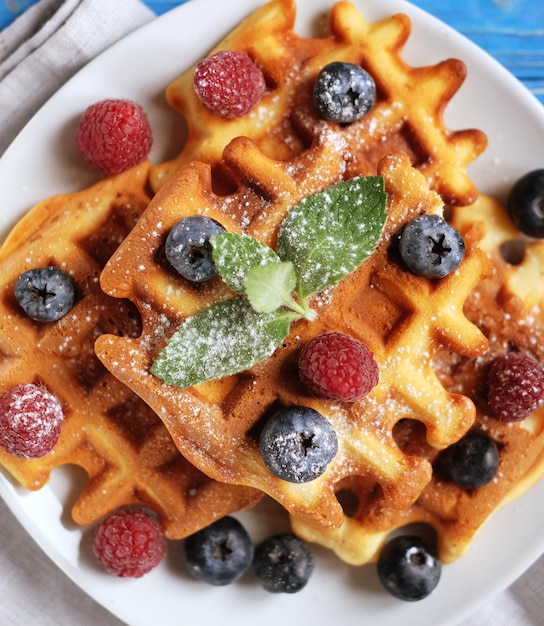 Traditional belgian waffles with fresh berrys and sugar powder on white plate