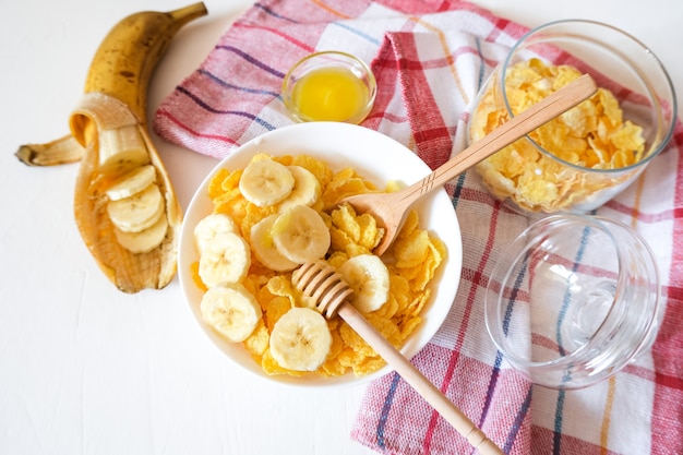 Traditional breakfast cereal of cornflakes and milk with a banana