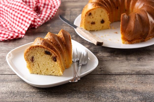 Traditional bundt cake piece with raisins on wooden table