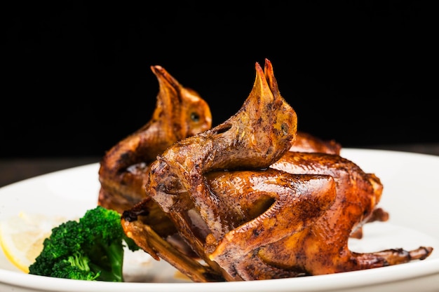 Traditional Cantonese roast pigeon on a and white porcelain plate