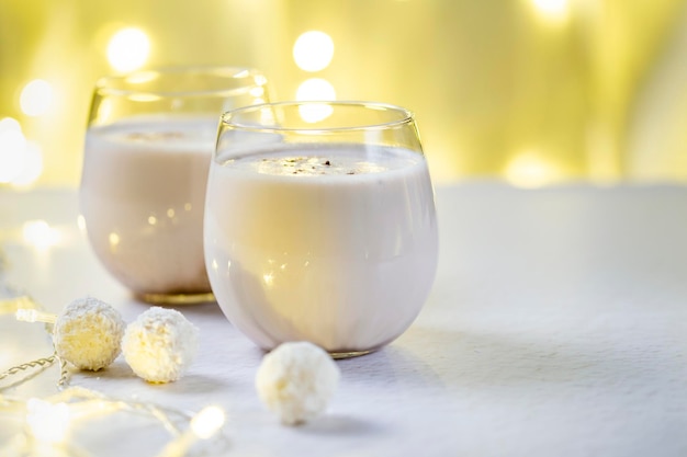 Traditional Christmas egg nog drink made from raw eggs on a light bokeh background from garland