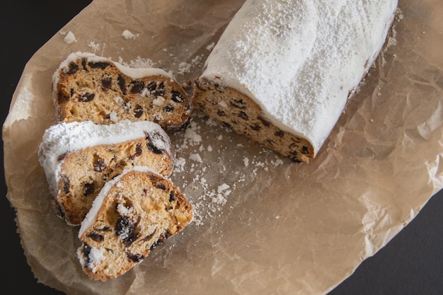 Traditional Christmas stollen made of dried fruits and nuts sprinkled with powdered sugar