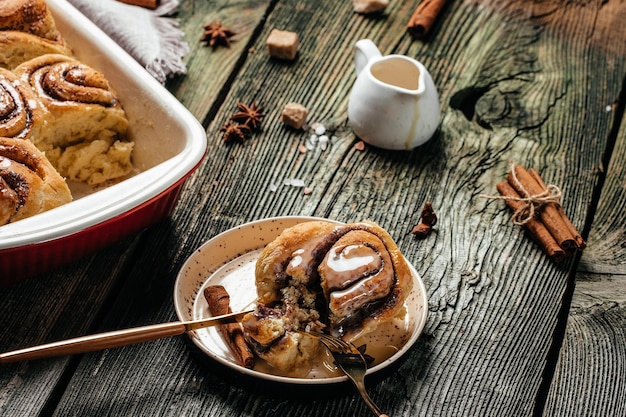 Traditional Cinnamon Rolls with white cream sauce on wooden background. banner, menu, recipe place for text, top view,