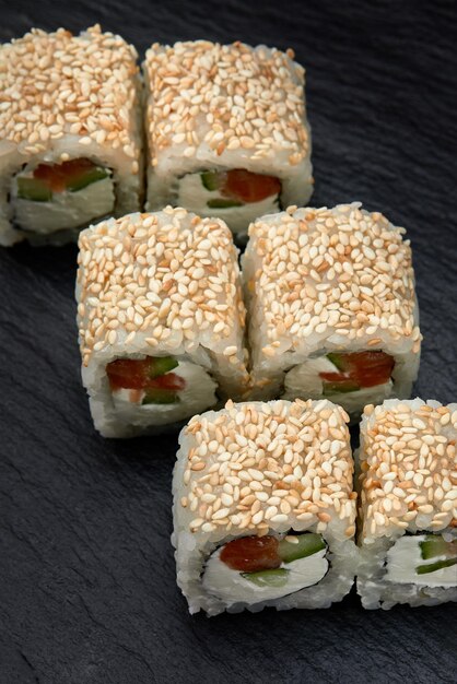 Traditional delicious fresh sushi roll set on a black background Sushi roll with rice cream cheese avocado salmon sesame Philadelphia Sushi menu Japanese kitchen restaurant