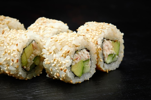 Traditional delicious fresh sushi roll set on a black background Sushi roll with rice cream cheese avocado salmon sesame Philadelphia Sushi menu Japanese kitchen restaurant