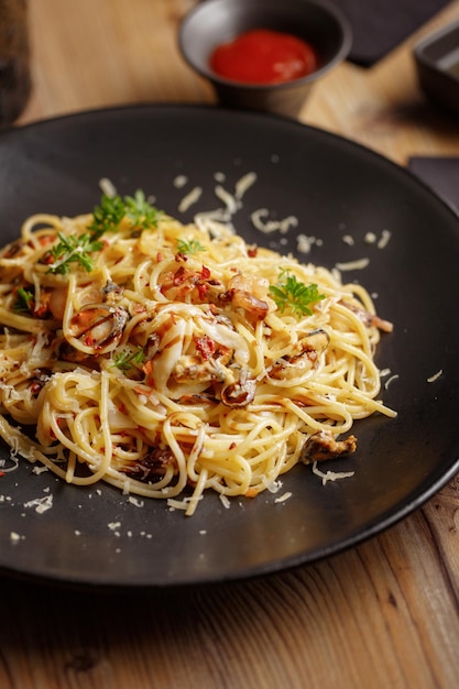 A traditional dish of Italian pasta cuisine restaurant serving black plate wooden table