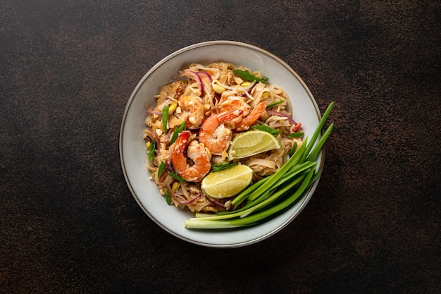 Traditional dish Pad Thai with shrimp on a dark background, top view