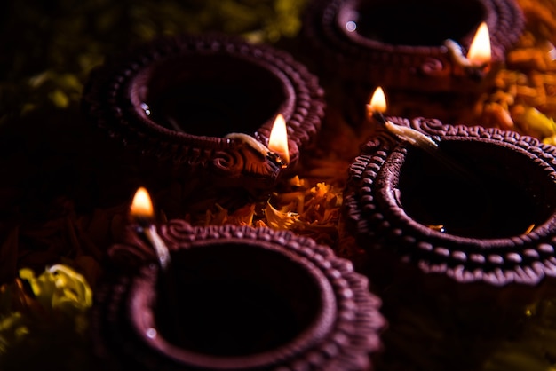 Photo traditional diya or oil lamp lit on colorful rangoli made up of flower petal, on the festival of lights called diwali or deepawali, selective focus