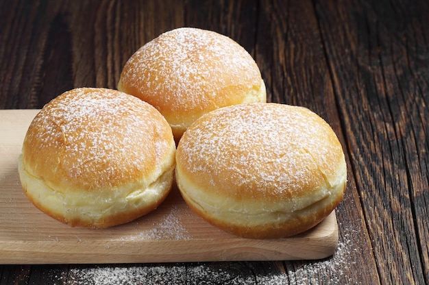 Traditional doughnuts with powdered sugar on wooden table