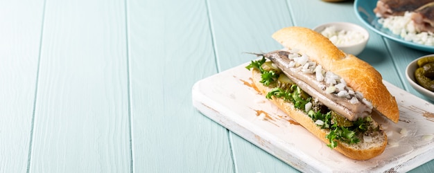 Traditional dutch snack, seafood sandwich with herring, onions and pickled cucumber. Broodje haring, copy space, banner