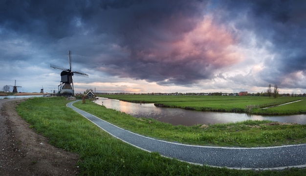 Photo traditional dutch windmills near water canals with cloudy sky, landscape