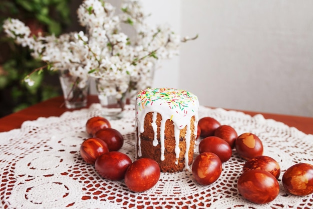 Traditional Easter cake with icing and hand painting eggs Homemade muffins with powdered sugar