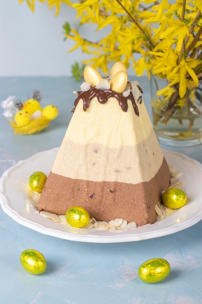 Traditional Easter curd dessert made of three types of chocolate white milk and black decorated with chocolate eggs