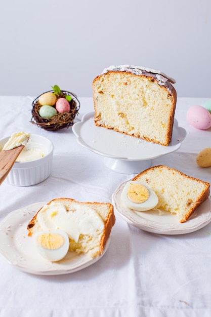 Traditional Easter meals Close view white plates with pieces of Paska bread and boiled eggs on each Tasty Easter breakfast food on table with white table cloth